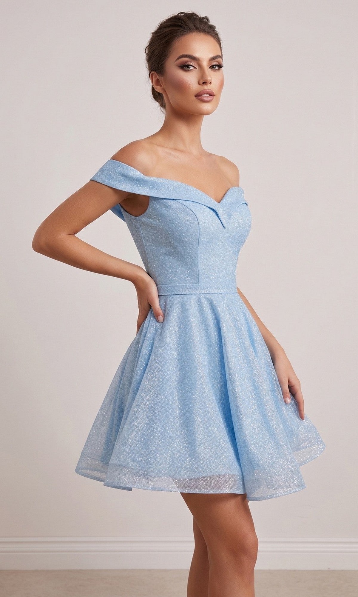 A woman models the Chicas C323 Short Homecoming Dress in baby blue, featuring a light off-the-shoulder design with a fitted bodice and flared glitter skirt, as she stands against a plain light background.